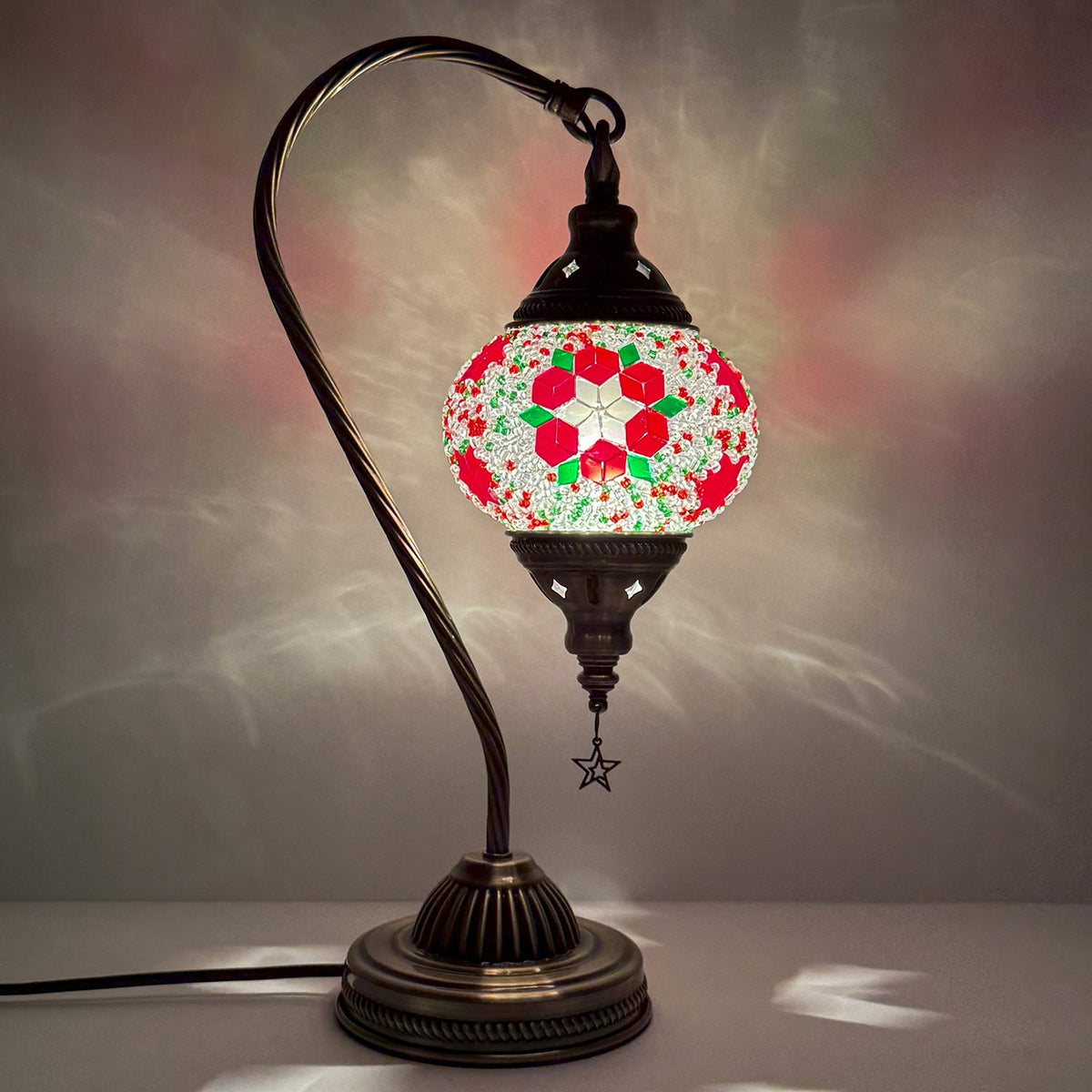 Mosaic swan lamp switched on, its pattern spread across the wall behind it
